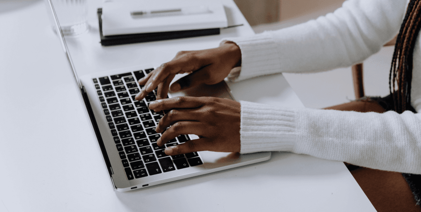 Black womans hands typing on a laptop